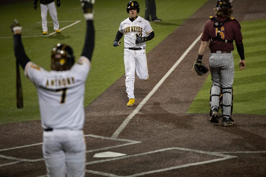Iowa catcher Ben Tallman runs toward home plate while teammate Keaton Anthony celebrates during a game between Iowa and Minnesota at Duane Banks Field in Iowa City on Friday, April 15, 2022. The Hawkeyes defeated the Golden Gophers, 9-3. Tallman had three hits in four at bats.