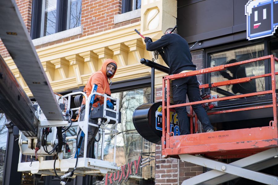 Signs and Designs installers Tanner Lamphier (left) and Clint Wrage (right) work on installing a sign for Tap Tap in the Ped Mall on Tuesday, April 26, 2022. 