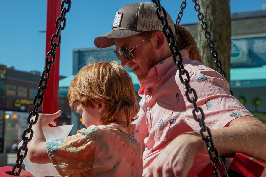Iowa City resident Lee Huisinga and his son Jack sit on the swing installation on the pedestrian mall in Iowa City on Saturday, June 18, 2022.