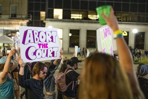 A Downtown Block Party attendee raises their cup to protesters during “Night of Rage,” an abortion-rights protest, in Iowa City on Saturday, June 25, 2022. The protest started at the Pentacrest with speakers, then, protesters marched through Iowa City.