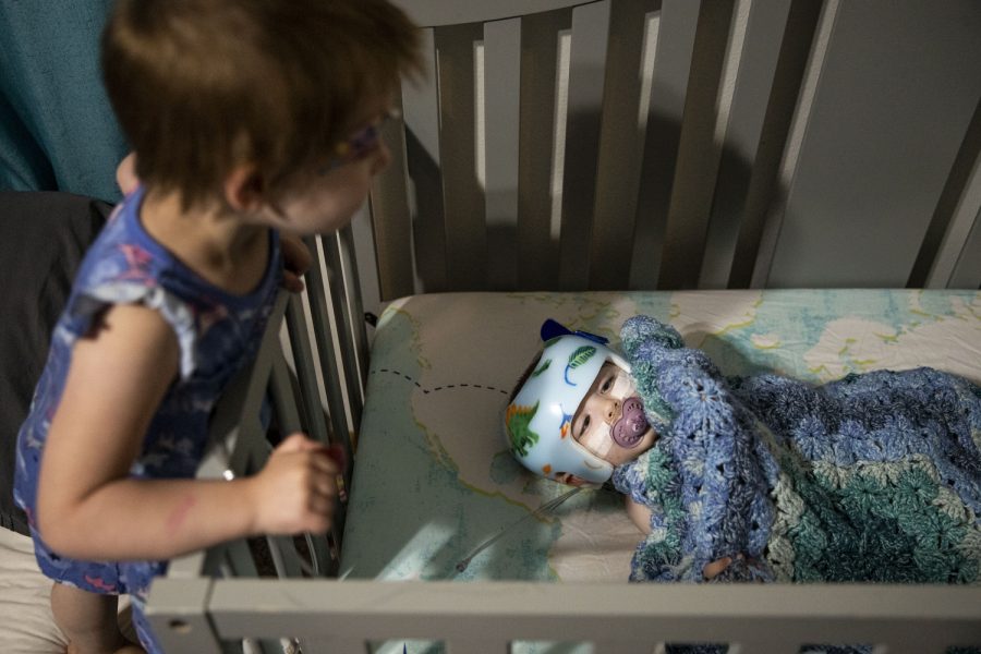 Lily looks over Mason before he falls asleep at their home in Iowa City on Thursday, June 23, 2022. Mason usually goes to bed around 7:30 p.m.