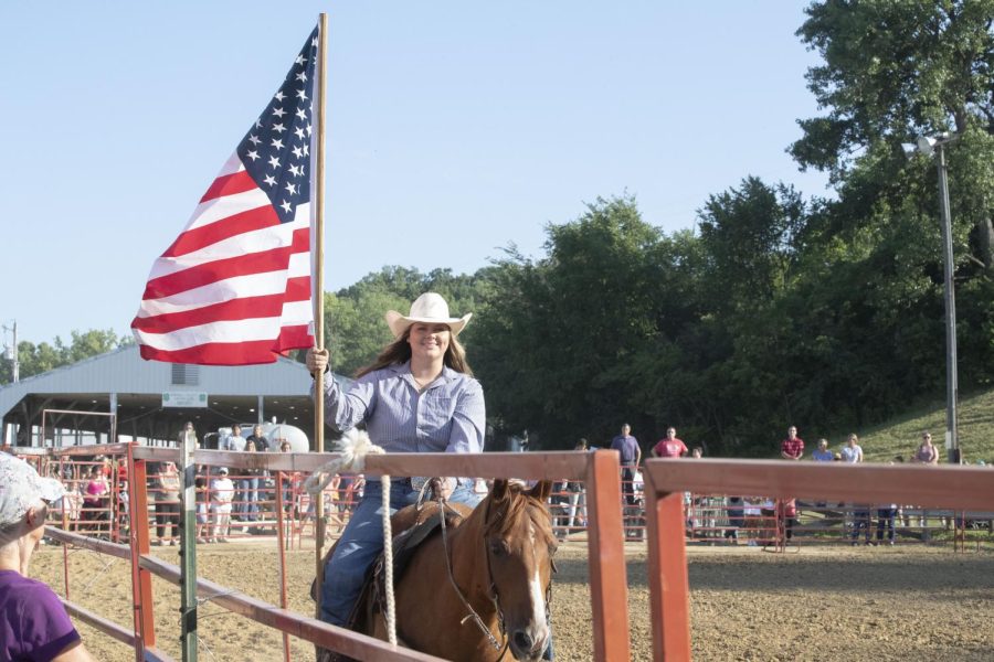 A flagbearer rides around the ring during the Sandburr Family Youth Rodeo at the Johnson County Fairgrounds in Iowa City on Wednesday, July 27, 2022.