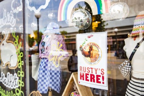 A poster promoting a downtown Iowa City scavenger hunt is taped inside the window of clothing store White Rabbit on South Linn Street on Monday, July 11, 2022. Starting July 1, the Iowa City Downtown District and Museum of Natural History started the “Where’s Rusty?” summer scavenger hunt for Iowa City families, which has hidden sloths in 29 different Iowa City businesses.