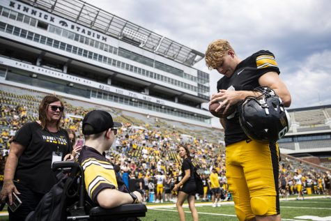 Iowa punter Tory Taylor signs a football for kid captain Adam Arp during Iowa football’s Kids’ Day at Kinnick in Iowa City on Saturday, Aug. 13, 2022. Iowa introduced its 2022 kid captains before the team practiced in front of fans.