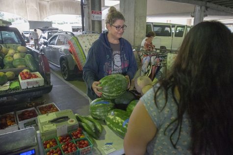Sam Wasson sells a watermelon at the Iowa City Farmers Market in the Chauncey Swan Ramp on Aug. 16, 2022.
