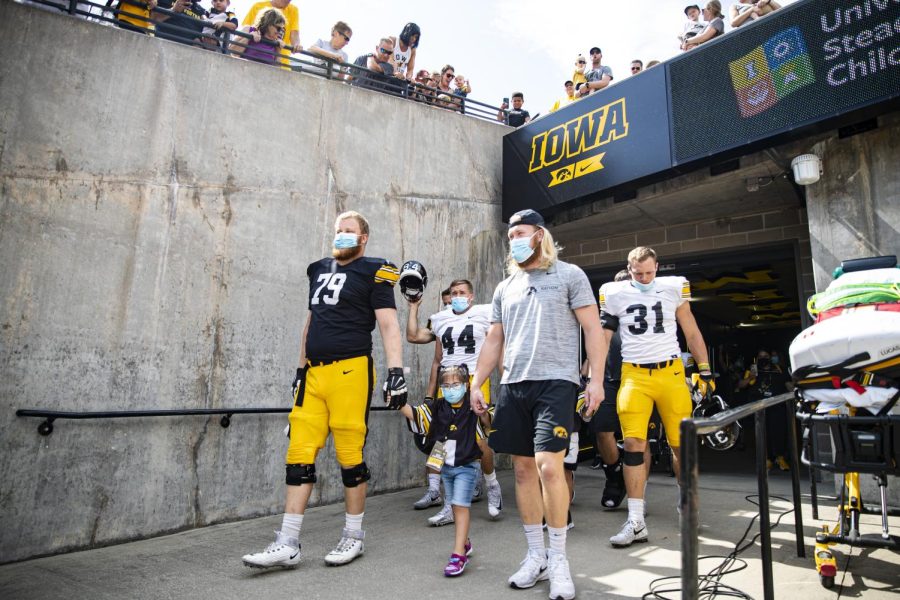 Kid captain Anjali Sahu walks out to the field with Iowa football players during Kid’s Day at Kinnick Stadium in Iowa City on Aug. 13, 2022. 