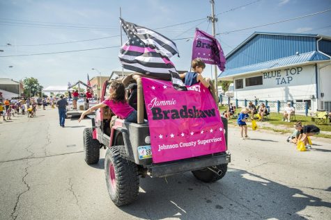 Harmony, 8, and John, 6, throw candy from the family’s Jeep during a parade in Lone Tree, Iowa, on Aug. 27, 2022. The family decided to paint the jeep hot pink to pay tribute to Jammie’s fight against breast cancer. 