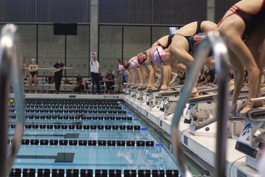Swimmers from Iowa and Nebraska get ready on the blocks before the start of a race. The Cornhuskers defeated the Hawkeyes, 175-123, on October 21, at the Campus Recreation and Wellness Center in Iowa City, Iowa. 