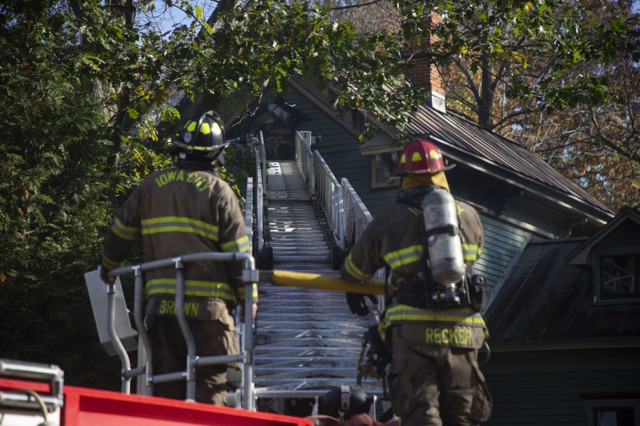 A firefighter walks up a ladder during a fire on Woodlawn Ave. in downtown Iowa City on Sunday, Oct. 23, 2022.