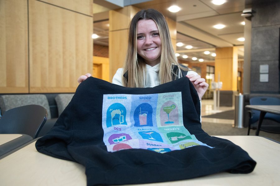 Entrepreneurial Finance student Isabelle Willey poses with a sweatshirt her group designed and made for a class project in Iowa City on Tuesday, Oct. 4, 2022. 