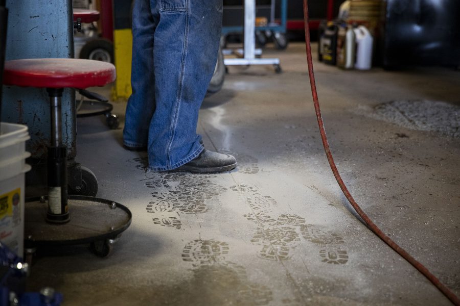 Phil works on a customer's car as his footprints can be seen in gravel dust that came off the car. A majority of his customers are regular customers and Anita contributes that to his honesty. Phil will often let a customer know if they can go without a repair or find it cheaper way to make the repair. (Ayrton Breckenridge/The Daily Iowan)