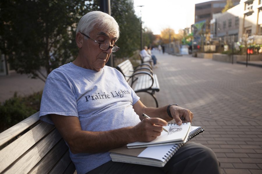 Artist Omer Sanan sits on a bench in the Pedestrian Mall and sketches people as the pass by in Iowa City on Friday, Oct. 21, 2022.