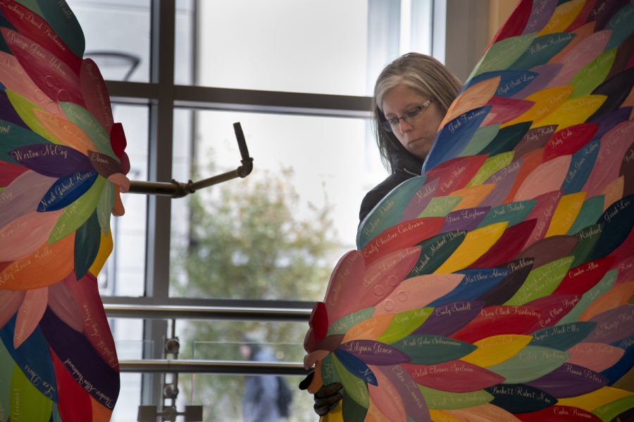 Krista Porter takes apart the No Foot Too Small art sculpture at the Iowa City Public Library Nov. 18, 2022. ) The wings raise awareness for pregnancy and infant loss; each feather being someone lost.