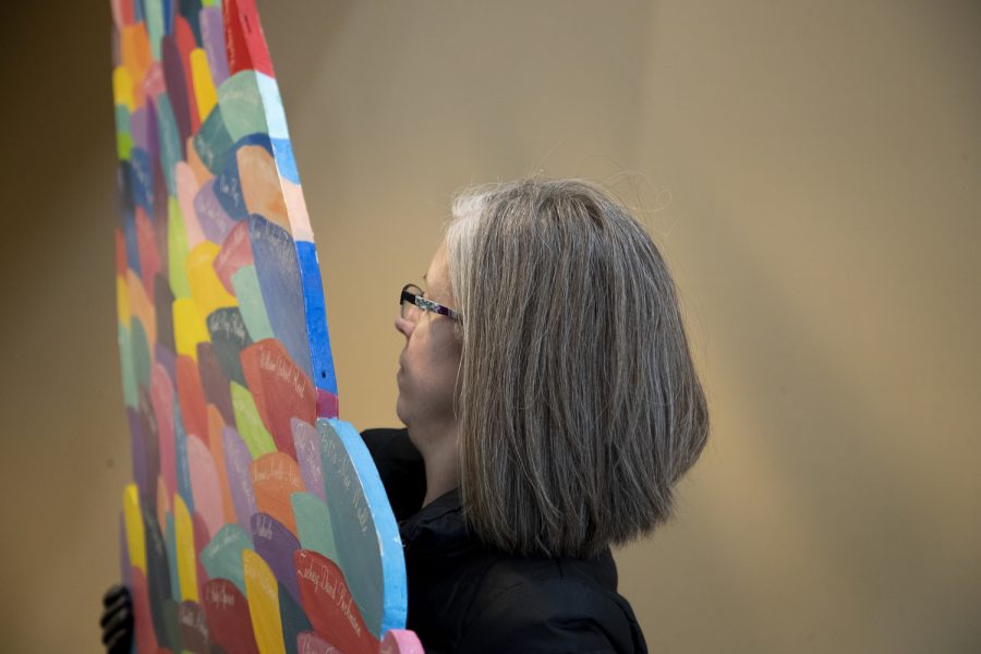 Krista Porter moves a wing of the No Foot Too Small art sculpture at the Iowa City Public Library Nov. 18, 2022. ) The wings raise awareness for pregnancy and infant loss; each feather being someone lost.