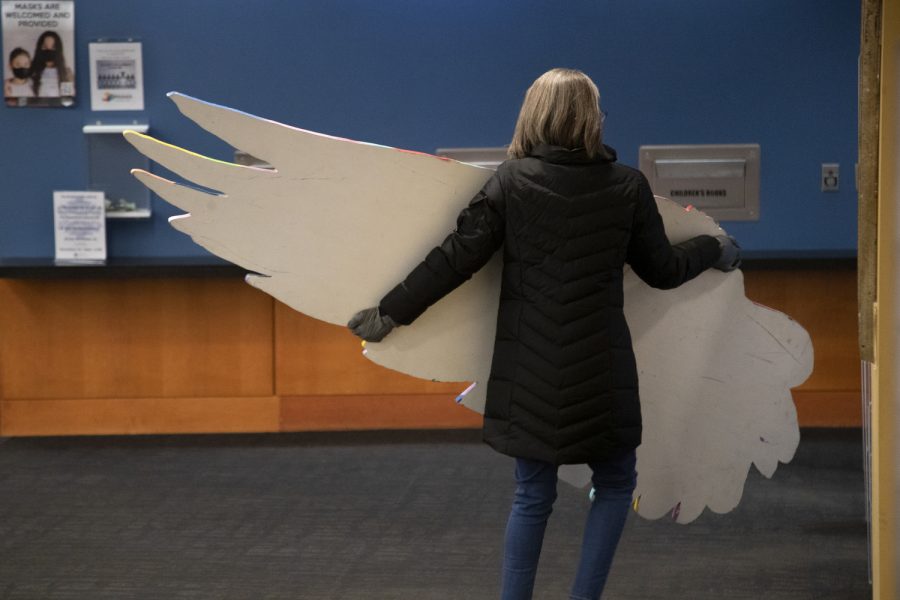 Krista Porter moves a wing of the No Foot Too Small art sculpture at the Iowa City Public Library Nov. 18, 2022. The wings raise awareness for pregnancy and infant loss; each feather being someone lost.