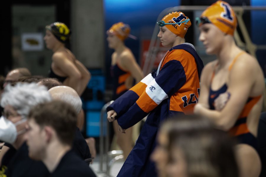 Illinois swimmer Sydney Stoll stretches behind the blocks to prepare for her event during a swim and dive meet between Iowa and Illinois in Iowa City on Friday, Jan 13, 2023. The Fighting Illini won the duel meet against the Hawkeyes, 46-45.