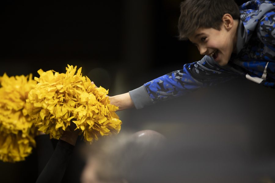 A fan reaches out to high-five cheerleaders after a wrestling meet between No. 2 Iowa and No. 11 Nebraska in Carver-Hawkeye Arena on Friday Jan. 20, 2023. The Hawkeyes defeated the Cornhuskers, 34-6.