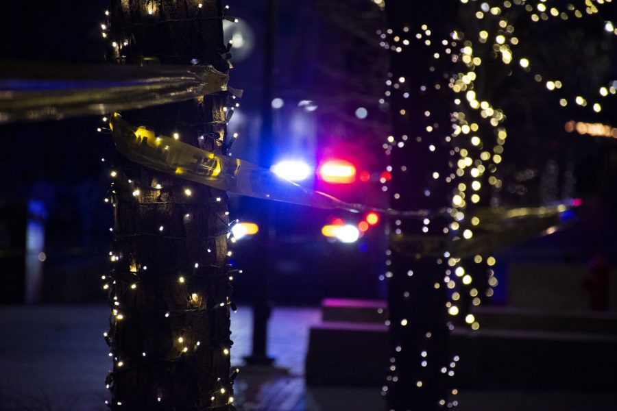 Police tape wraps around trees while a police car sits near the entrance of Brother’s Bar and Grill after reports of shots fired near the Pedestrian Mall on in Iowa City, Iowa on Saturday, Jan. 14, 2023. Officers were able to detain the shooter, no one is believed to have been injured.