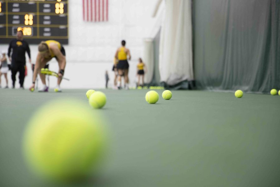 Iowa’s women’s tennis team pick up tennis balls during a women’s tennis meet at the Hawkeye Tennis & Recreational Complex on Friday, Feb. 24, 2023. The Cyclones defeated the Hawkeyes, 4-0.