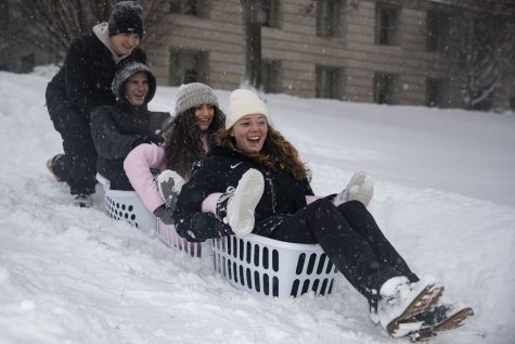 University of Iowa students Eli Chow, Ethan Holter, Rose Bishay and Madeline Fait (left to right) sled on the Pentacrest on Thursday, Feb. 16, 2023. Several classes were canceled because of the weather. Snow totals in Iowa City were as high as 10.5 inches. Bishay said, “We went to Target, bought two five dollar buckets and decided to make the best out of the weather.” (Ayrton Breckenridge/The Daily Iowan)