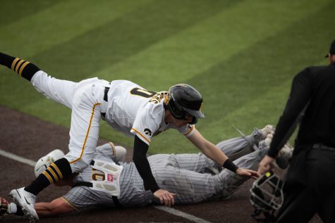 Iowa infielder Michael Seegers jumps over West Michigan catcher Greg Budig to score during a baseball game between Iowa and West Michigan at Duane Banks Field in Iowa City on Friday, March 24, 2023. The Hawkeyes defeated the Broncos, 9-3.