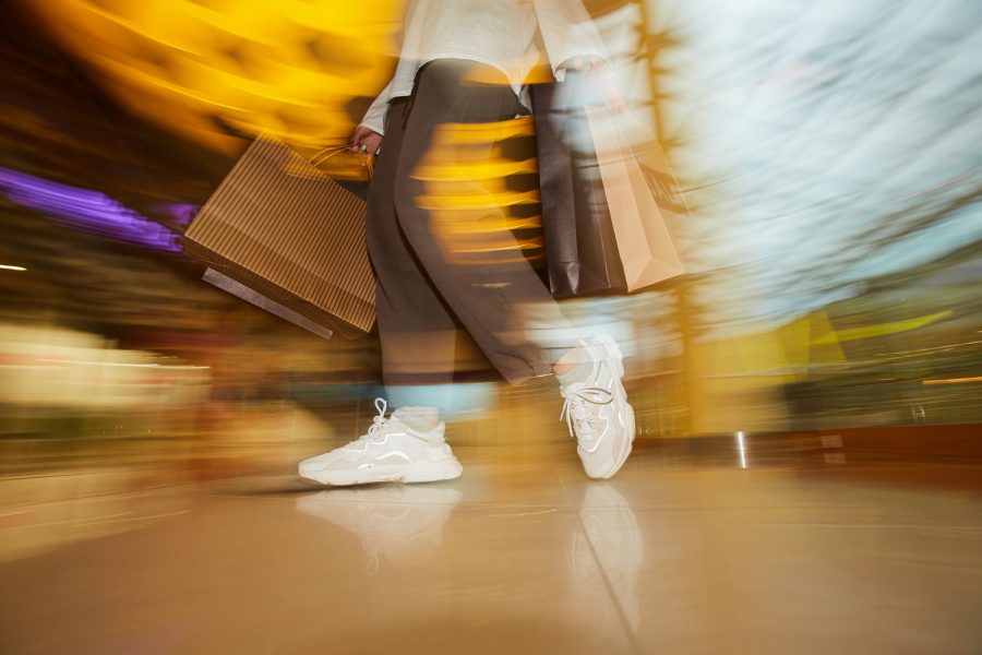 Blurred motion of woman standing with paper bags in the shop
