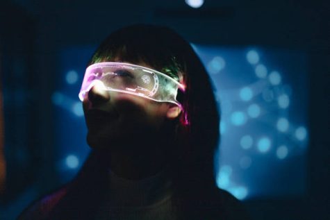 Excitement of asian teenage girl wearing virtual reality headset and gesturing while touching air during the VR experience in colorful UV lighting at dark night.Innovation