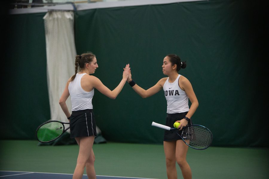 Iowas Marisa Schmidt and Daianne Hayashida high-five during their doubles match at the Hawkeye Tennis & Recreational Complex in Iowa City, on Friday, March 31, 2023. Schmidt and Hayashida won their doubles match.