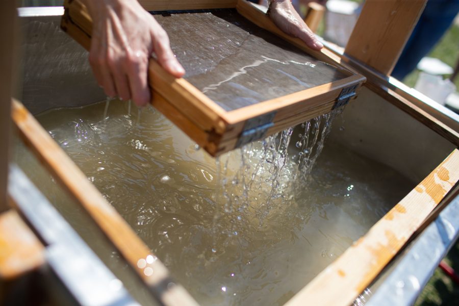 A volunteer practices papermaking in a vat during a Japanese papermaking festival in Iowa City on Friday, April 14, 2023.