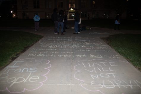 University of Iowa students write with chalk on the Pentacrest in support of the transgender community on Monday evening, April 17, 2023. The event took place two days before political commentator Matt Walsh is set to arrive to Iowa’s campus. 