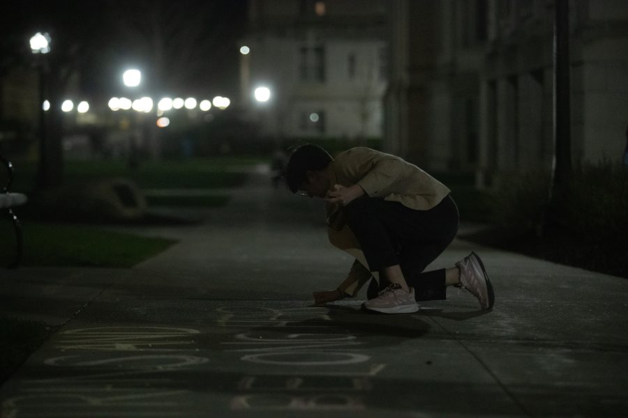 University of Iowa students write with chalk on the Pentacrest in support of the transgender community on Monday evening, April 17, 2023. The event took place two days before political commentator Matt Walsh is set to arrive to Iowa’s campus. 