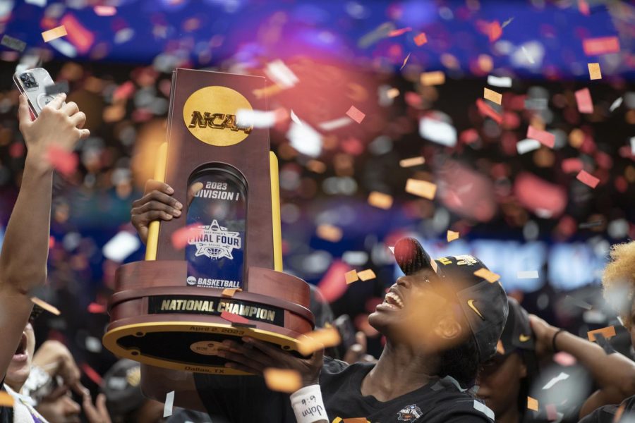 LSU forward Flau,jae Johnson holds up the national championship trophy after winning the NCAA title over Iowa, 102-85, at the American Airlines Center in Dallas on Sunday, April 2, 2023.