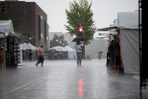 Iowa City residents walk in the rain during day one of the 2023 Summer of the Arts Festival on Friday, June 2.