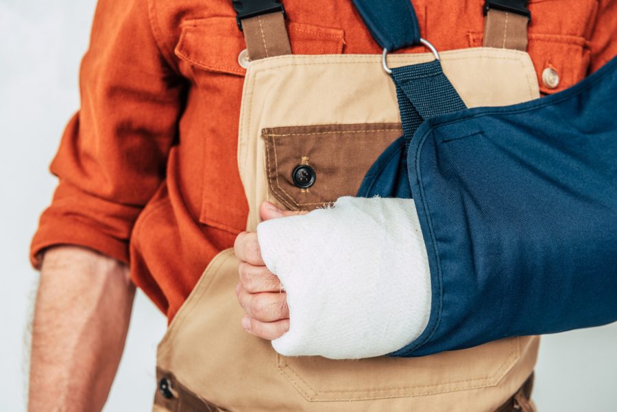 Cropped view of repairman with broken arm and bandage on white background