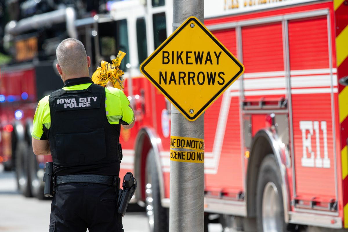 An Iowa City Police Officer takes off barricade tape at a crime scene on the corner of west Burlington st. and south Riverside Drive on Thursday, July 13 2023. 