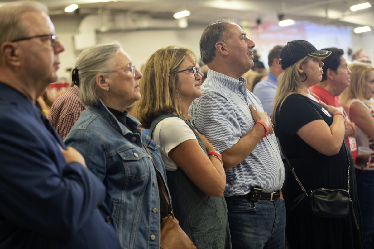Attendees stand for The Pledge of Allegiance during Ashley Hinson’s BBQ Bash at Hawkeye Downs in Cedar Rapids, Iowa on Sunday, August 6, 2023.