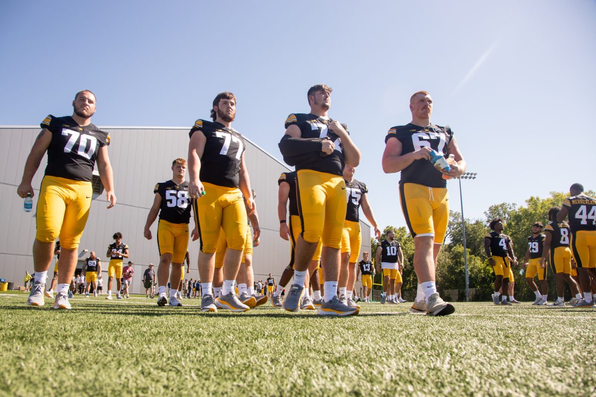 Connor Colby, second from left, and other Iowa offensive linemen walk onto the field during Iowa football media day in Iowa City on Aug. 11. 