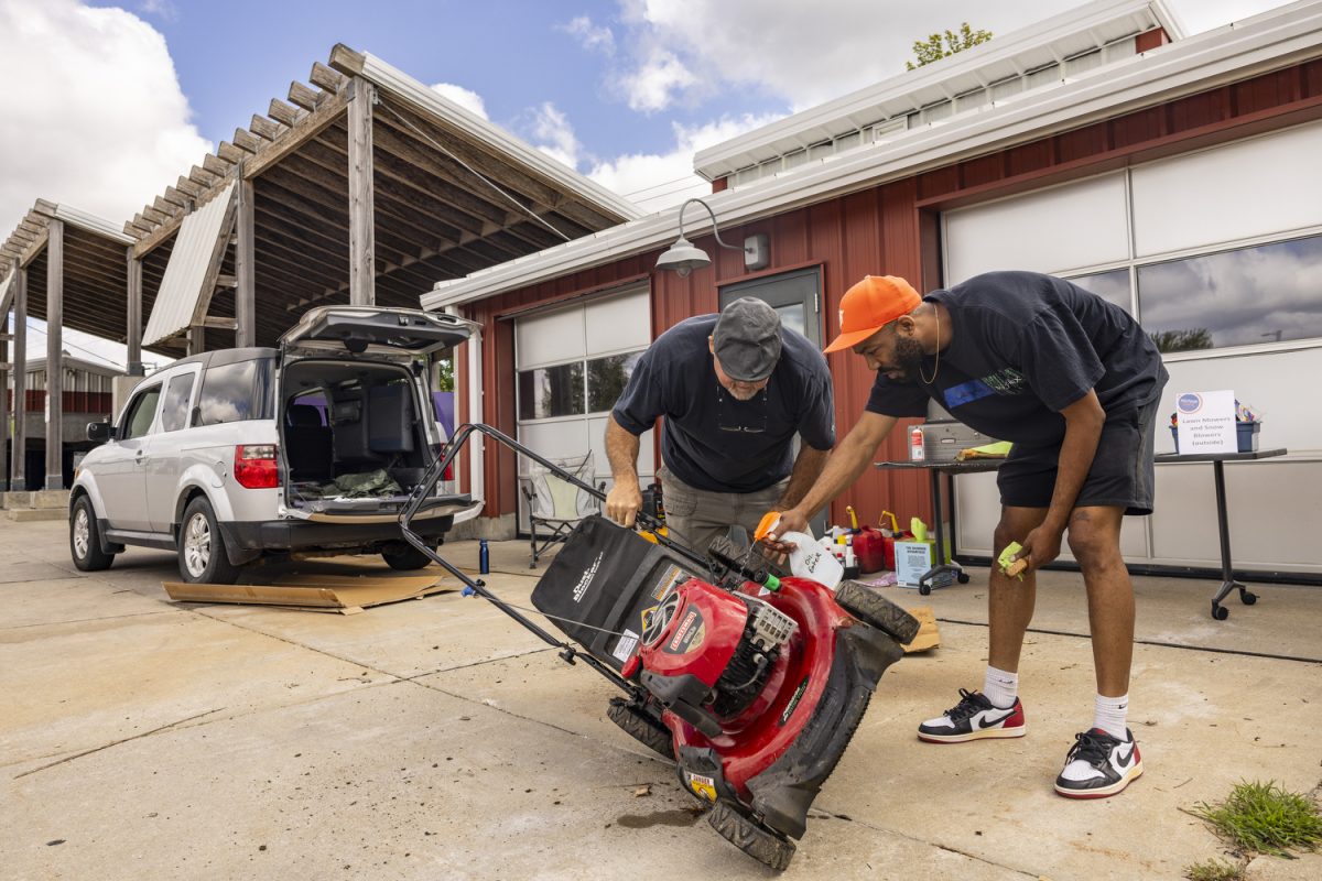 Keith Barkalow (left) and Demetrius Perry (right) spray down Perry’s lawnmower during the second Iowa City Repair Cafe at the Eastside Recycling Center on Sunday, Aug. 27, 2023. Numerous volunteers who specialized in different trades repaired household items from fans to lawnmowers. Barkalow has been fixing up lawnmowers and other machinery for about six years, repairing items at his home and also helping community members. 