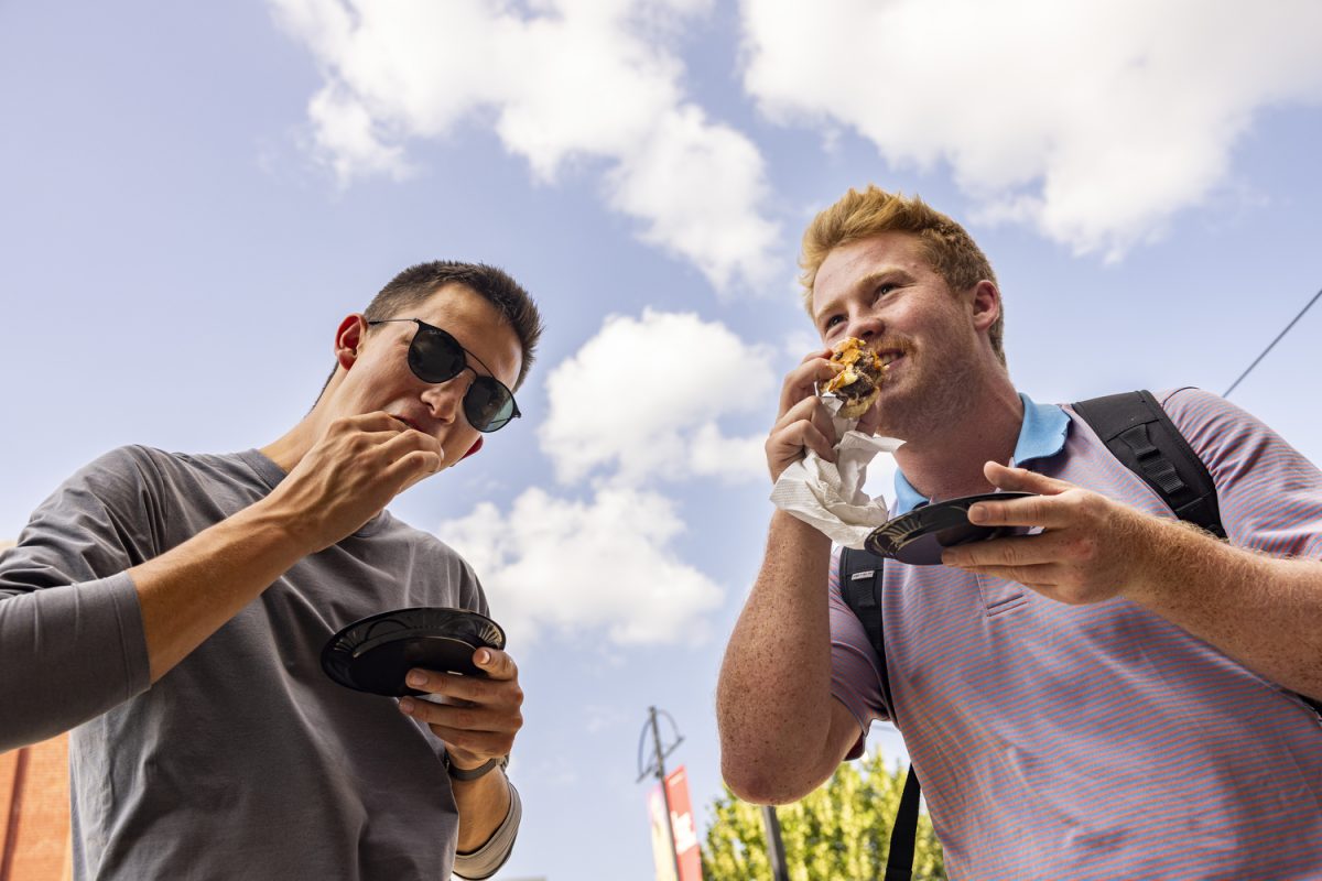 University of Iowa third-year students Ben Hill (left) and George Wolfe (right) enjoy burgers during the 15th Annual Taste of Iowa City downtown on Tuesday, Aug. 29, 2023. After postponing the event for a week because of extreme heat, community members congregated downtown to enjoy diverse cuisine from over 50 participating restaurants. 
