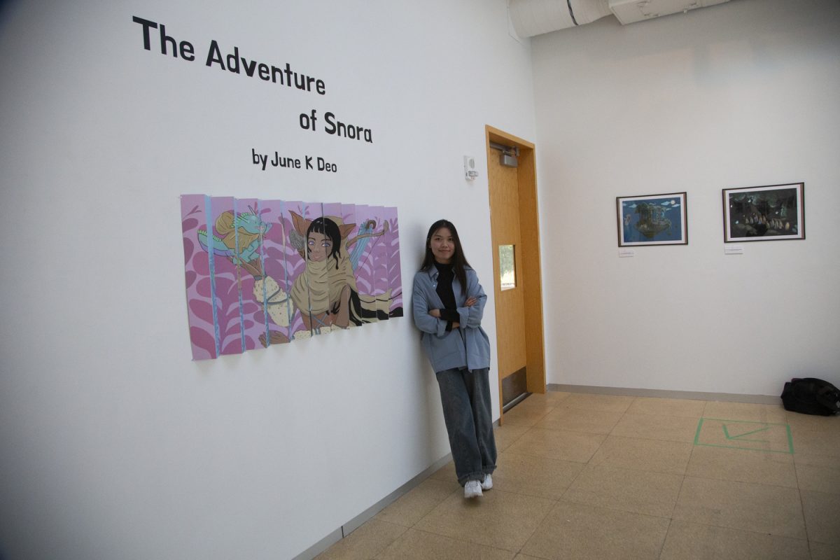 June Deo poses for a portrait with her latest work The Adventure of Snora presented in a fine art gallery in the Visual Arts building in Iowa City on Wednesday, Oct. 11, 2023.