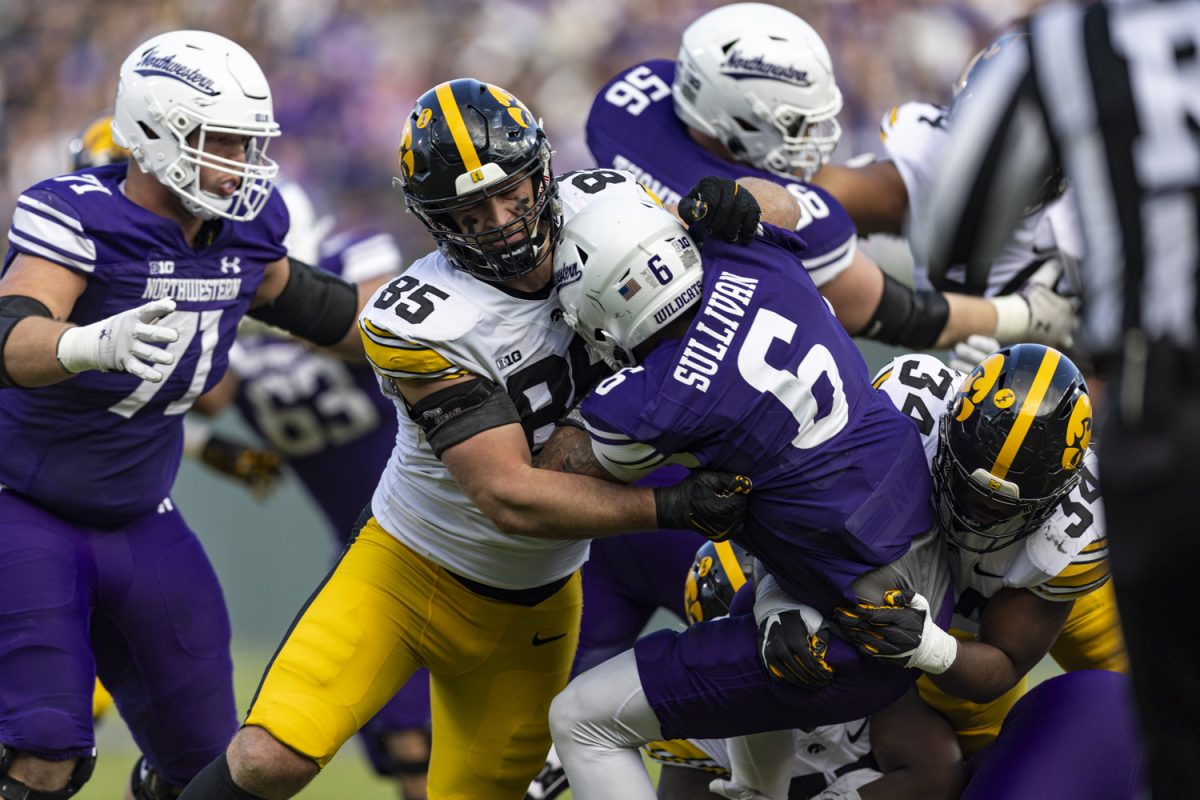 Iowa defensive lineman Logan Lee and linebacker Jay Higgins tackle Northwestern quarterback Brendan Sullivan during the 2023 Wildcats Classic, a football game between Iowa and Northwestern at Wrigley Field in Chicago, on Saturday, Nov. 4, 2023. Lee had four total tackles. The Hawkeyes defeated the Wildcats, 10-7.