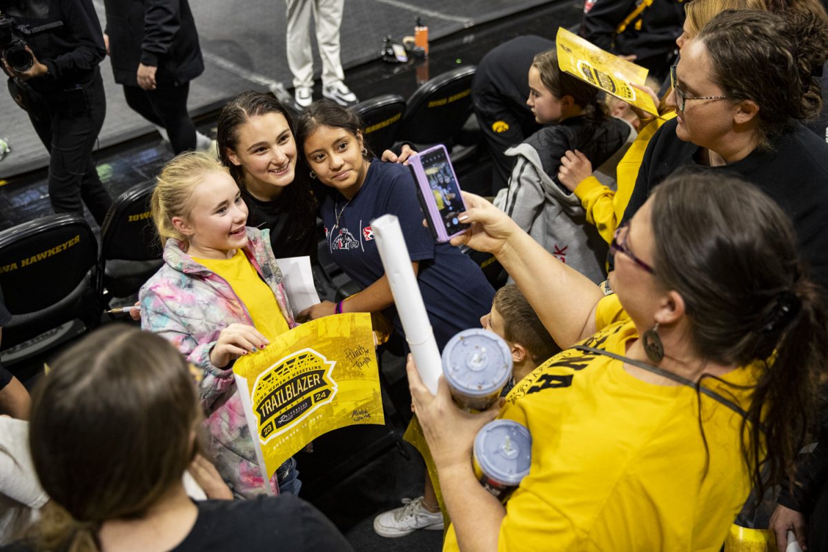 Iowa’s No. 2 136-pound Nanea Estrella takes a picture with fans after the Trailblazer Duals between No. 3 Iowa, No. 6 Sacred Heart, No. 13 Presbyterian, and No. 11 Lindenwood at Carver-Hawkeye Arena on Sunday, Nov. 12, 2023. Iowa women’s wrestling made history on Sunday, hosting the first women’s wrestling dual in Carver-Hawkeye Arena. The Hawkeyes defeated Presbyterian, 44-1, Lindenwood, 43-0, and Sacred Heart, 40-4. (Ayrton Breckenridge/The Daily Iowan)