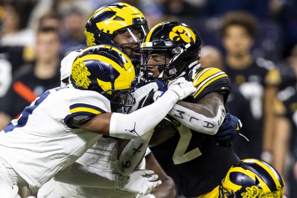 Michigan players tackle Iowa running back Kaleb Johnson during a football game between No. 18 Iowa and No. 2 Michigan at Lucas Oil Stadium in Indianapolis on Saturday, Dec. 2, 2023. The Wolverines lead the Hawkeyes, 10-0, after the first half (Cody Blissett/The Daily Iowan)