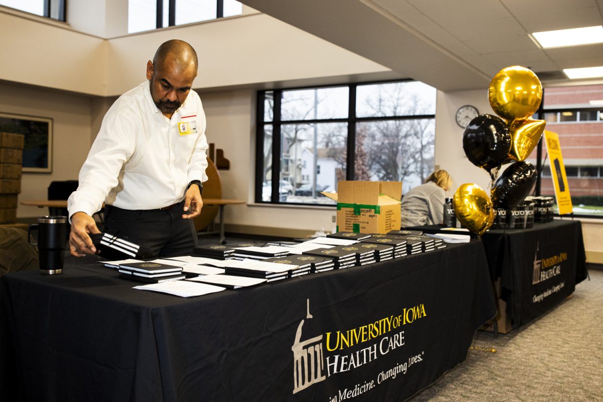 University of Iowa Health Care Information and Technology Function Representative Warren Staal sets down free UIHC notebooks before a Mercy signage changing at the University of Iowa Health Care Downtown Campus building in Iowa City on Wednesday, Jan. 31. (Cody Blissett/The Daily Iowan)