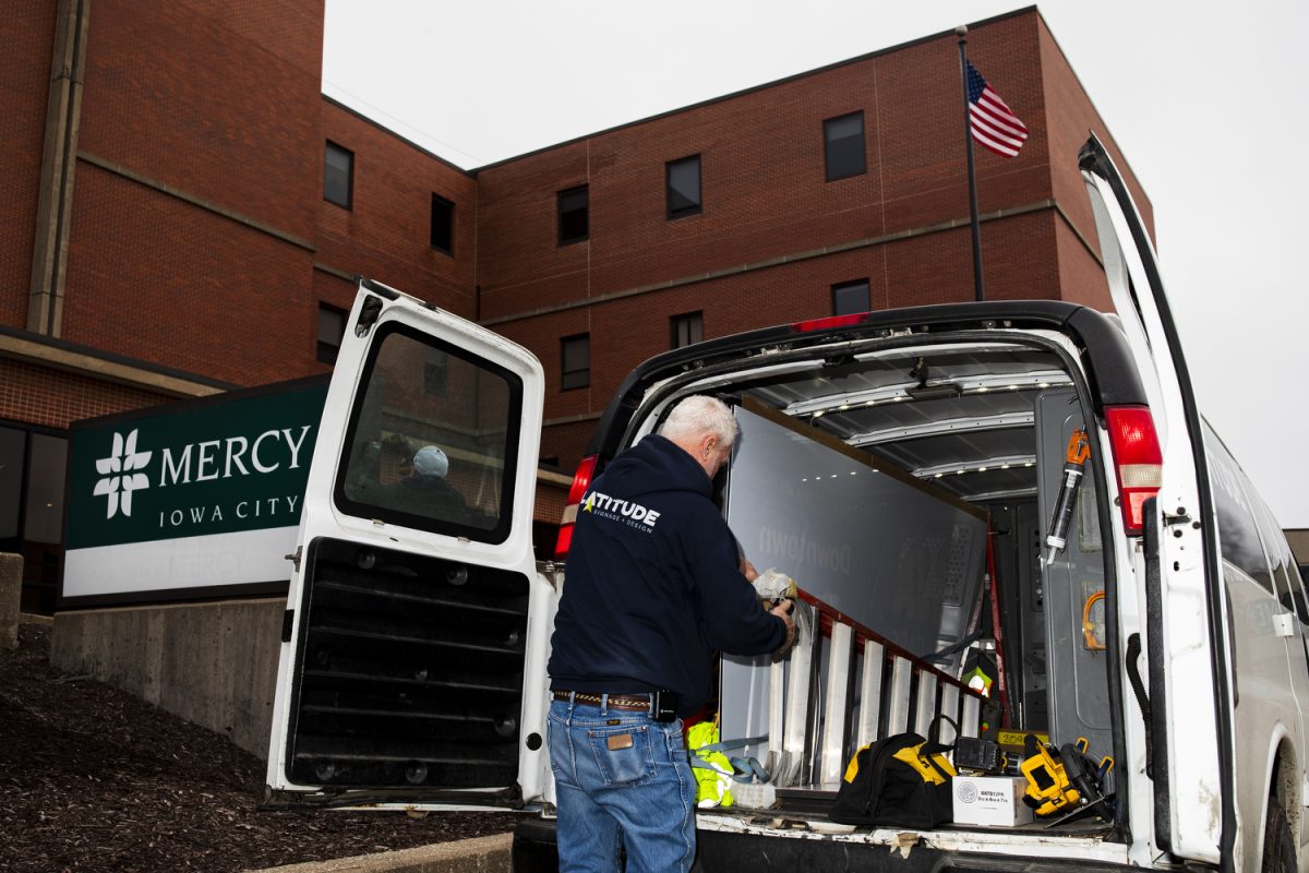 A Latitude employee moves a ladder during a Mercy signage changing at the University of Iowa Health Care Medical Center Downtown Campus in Iowa City on Wednesday, Jan. 31. 