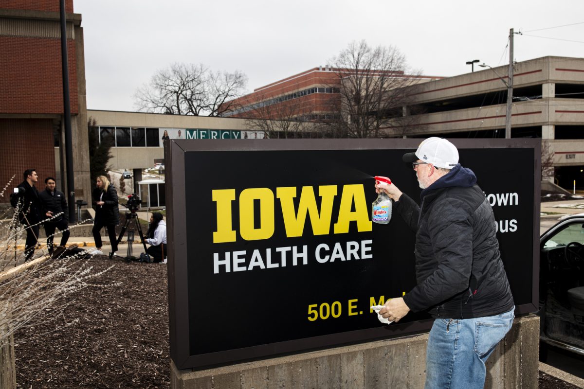 A Latitude worker cleans the new sign with Windex during a Mercy signage changing at the University of Iowa Health Care Downtown Campus building in Iowa City on Wednesday, Jan. 31. (Cody Blissett/The Daily Iowan)