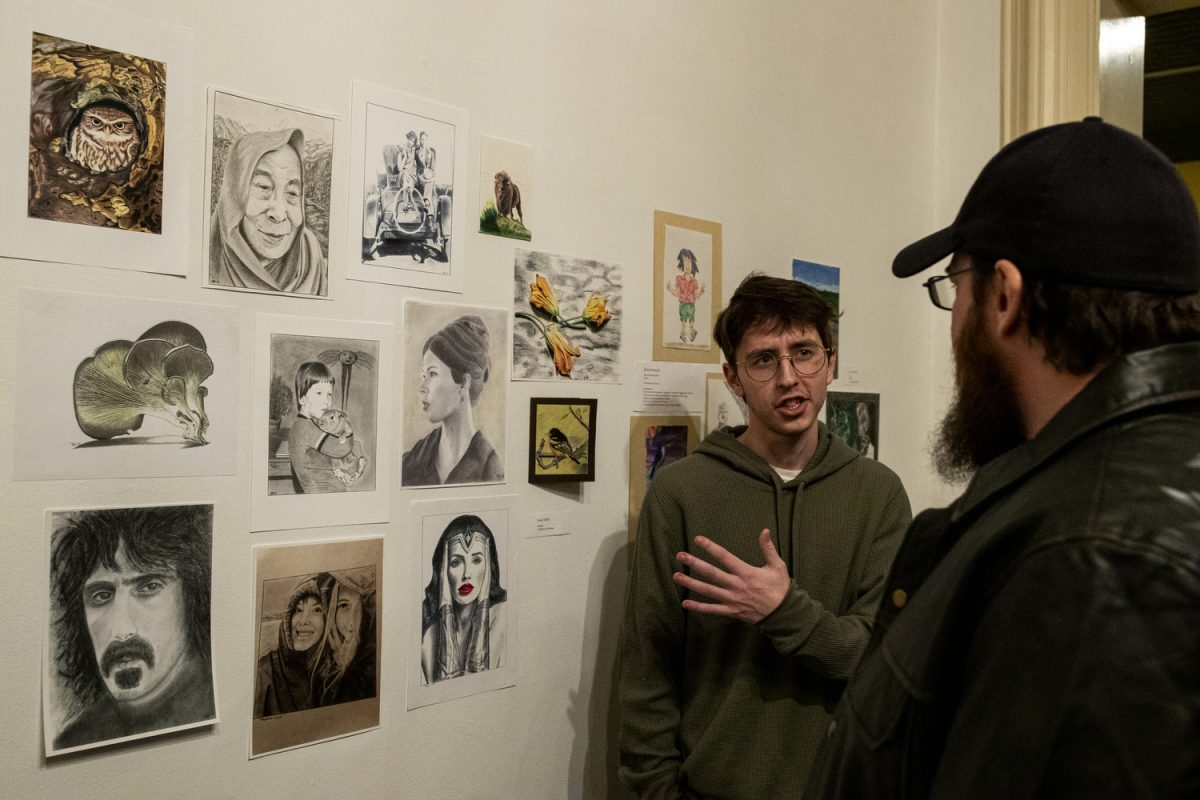 An attendee speaks with artist Jesse Miller during a art gallery opening for formally incarcerated artists hosted by Inside Out Reentry at Public Space One in Iowa City on Friday, Feb. 2, 2024.
