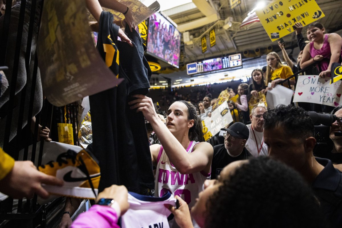Iowa guard Caitlin Clark signs merchandise during a basketball game between No. 4 Iowa and Illinois inside a sold-out Carver-Hawkeye Arena in Iowa City, Iowa, on Sunday, Feb. 25, 2024. The Hawkeyes defeated the Fighting Illini, 101-85.