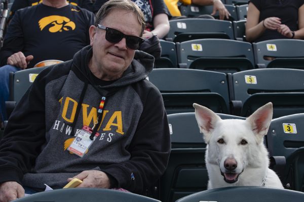 Iowa fan Kirk Nelson poses for a portrait with his service dog Rosie, named after the Rose Bowl. The Hawkeyes defeated the Huskies, 14-6, during a baseball game between No. 18 Iowa and Northern Illinois at Duane Banks Field on Tuesday, Feb. 27, 2024. 