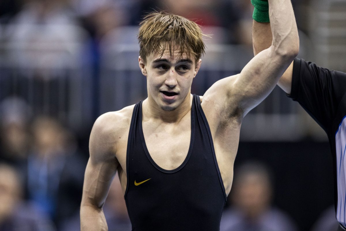 An official holds up Iowa 125-pound Drake Ayala’s arm during the fourth session of the NCAA Men’s Wrestling Championships at T-Mobile Center in Kansas City, Missouri, on Friday, March 22, 2024. Ayala defeated Wisconsin Eric Barnett by decision, 3-2.